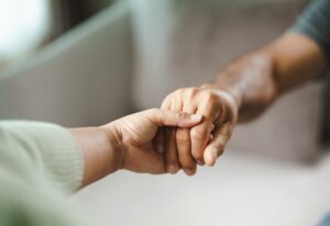 One adult holding the hand of another during outpatient mental health treatment.