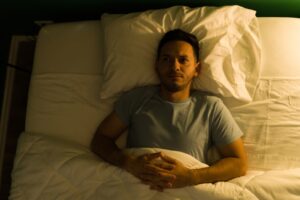 A man lies in bed awake because a mental health issue is interfering with his sleep.