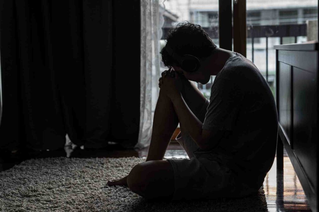 Person sitting alone on the floor in a dark room, reflecting loneliness and its impact on mental health