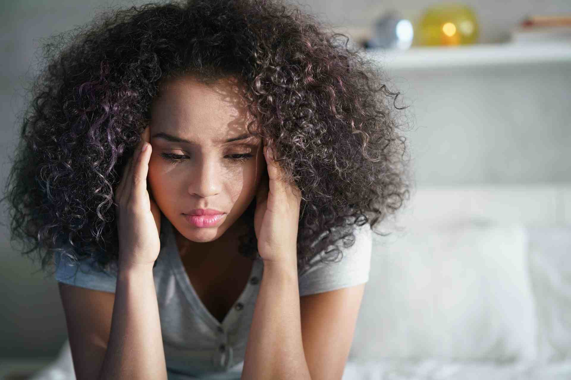 Woman holding head feeling stressed and anxious in the morning