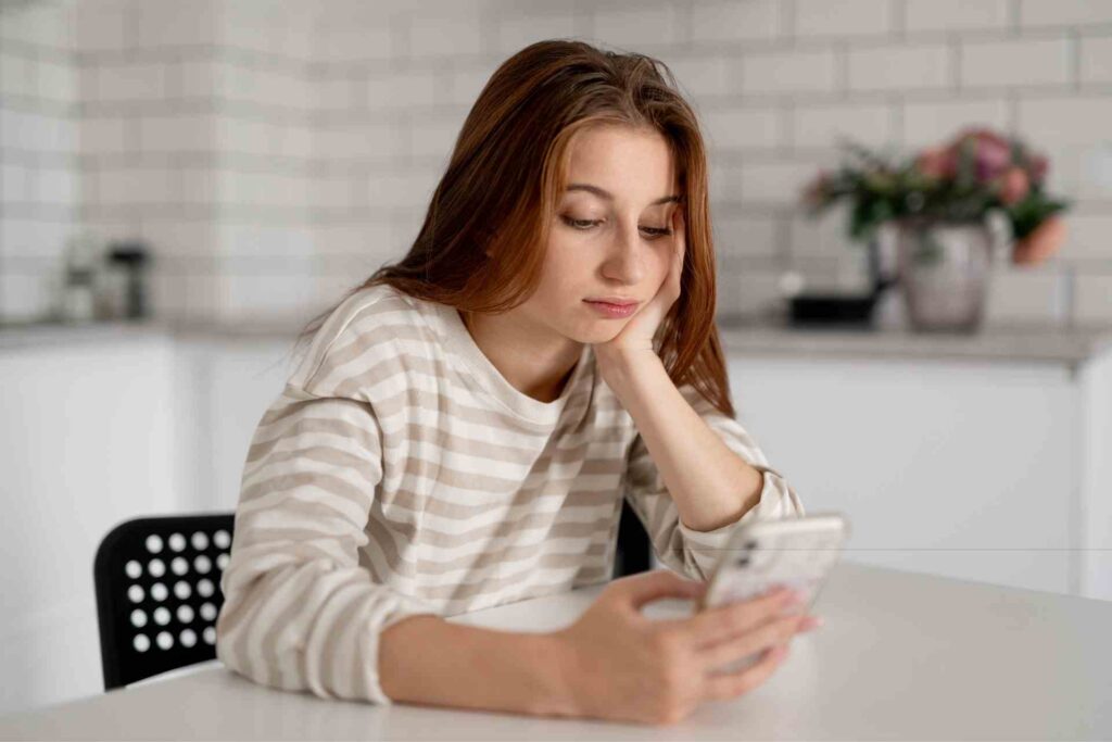 Young woman looking at her phone with a worried expression, illustrating anxiety and rumination.