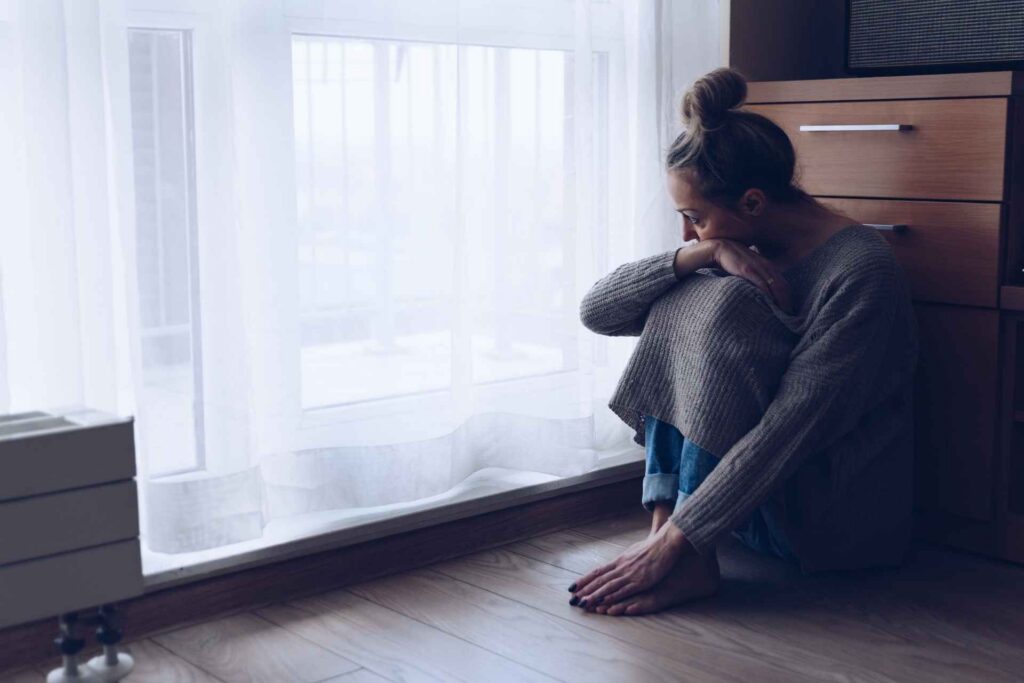 Woman sitting alone while experiencing symptoms of anxiety and depression